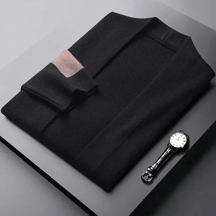 Schwarzer Herrenpullover aus Wolle, elegant gefaltet, neben einer Armbanduhr auf grauem Hintergrund.