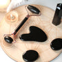 Schwarzer Jade-Roller und Gua Sha Set auf Holzplatte, Gesichtsmassage, Hautpflege-Tool.