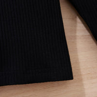 Schwarzes geripptes Langarmshirt aus Baumwolle auf Holztisch, Detailansicht.