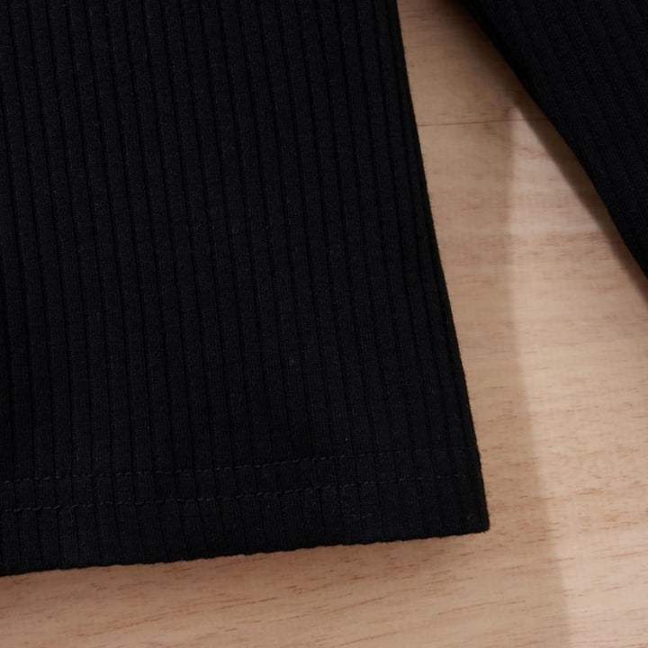 Schwarzes geripptes Langarmshirt aus Baumwolle auf Holztisch, Detailansicht.