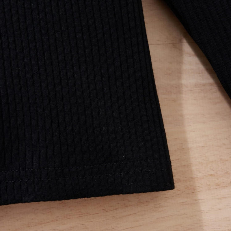 Schwarzes geripptes Langarmshirt aus Baumwolle auf Holztisch, Detailansicht.