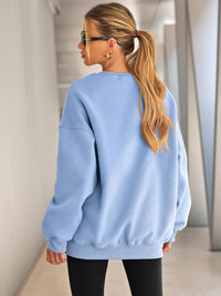 Frau in hellblauem Oversize-Pullover, blonde Haare, Sonnenbrille, moderne Mode.