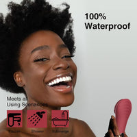 Frau mit Afro, hält roten wasserdichten Vibrator, lächelnd, 100% wasserdicht, für Dusche geeignet.