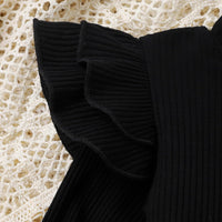 Schwarzes geripptes Oberteil mit Rüschenärmel auf gehäkeltem Hintergrund, Damenmode.