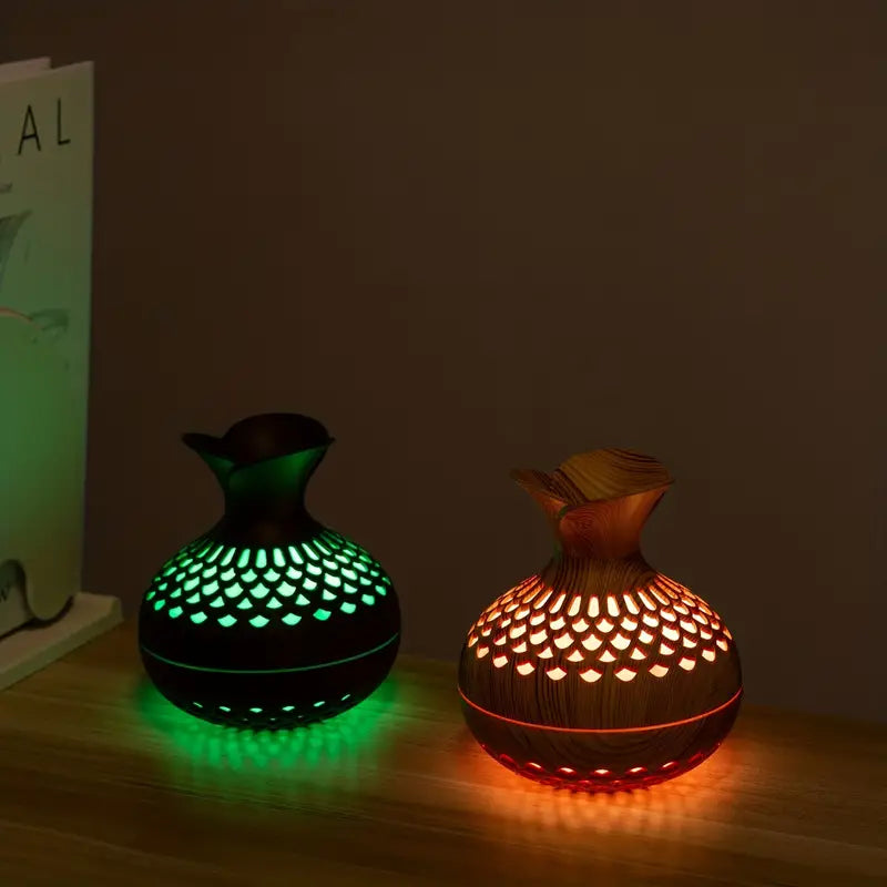 Zwei LED-Aromadiffusoren aus Holzoptik, grün und orange leuchtend, auf Holztisch.