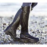 Schwarze Lederreitstiefel am Strand, robustes Design, ideal für Outdoor-Aktivitäten.