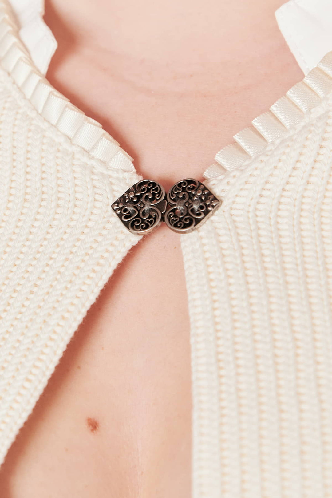 Weiße Strickjacke mit dekorativem Metallverschluss, elegantes Design, Damenmode.