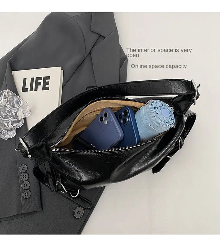 Schwarze Ledertasche mit Smartphone, Zeitschrift und Kleidung, offene Innenansicht.