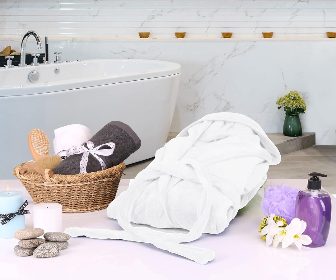 Weiße Bademantel aus Baumwolle im luxuriösen Badezimmer mit Badewanne und Wellness-Accessoires.