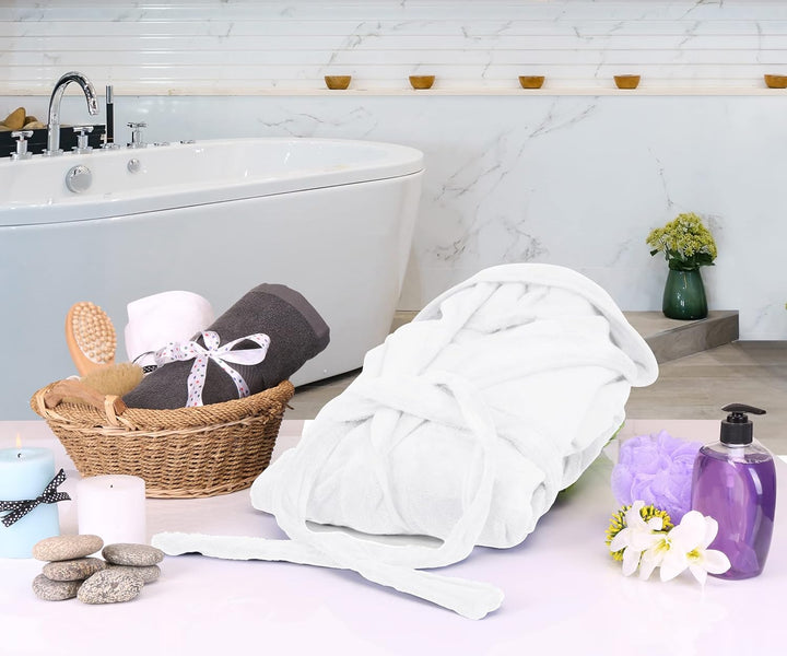 Weiße Bademantel aus Baumwolle im luxuriösen Badezimmer mit Badewanne und Wellness-Accessoires.