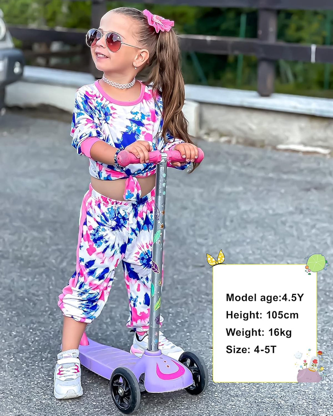 Mädchen auf lila Kinderroller, bunte Kleidung, Sonnenbrille, draußen, Freizeitaktivität.
