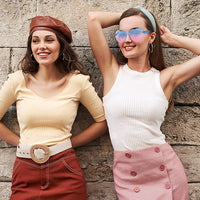 Zwei Frauen in modischer Kleidung, eine mit braunem Barett, die andere mit blauer Sonnenbrille.