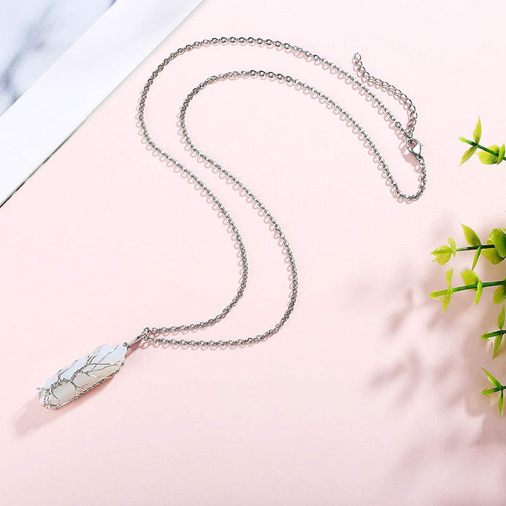 Silberne Halskette mit weißem Marmoranhänger auf rosa Hintergrund, eleganter Schmuck.