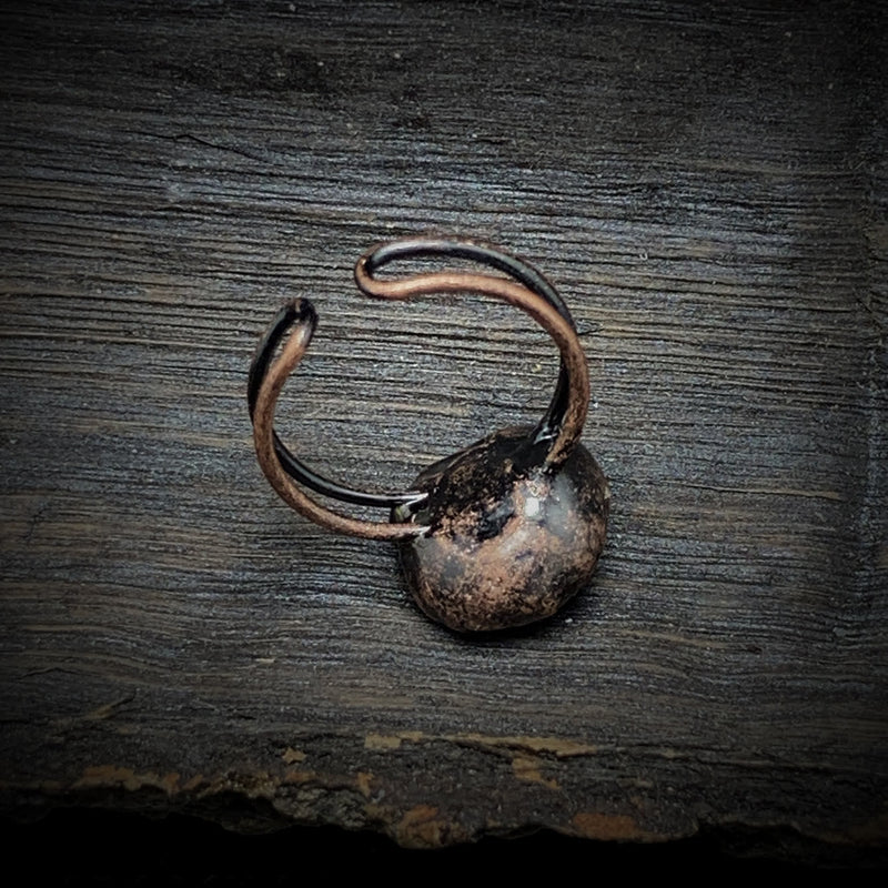 Antiker bronzener Ring auf Holzoberfläche, rustikales Schmuckdesign, Vintage-Stil.