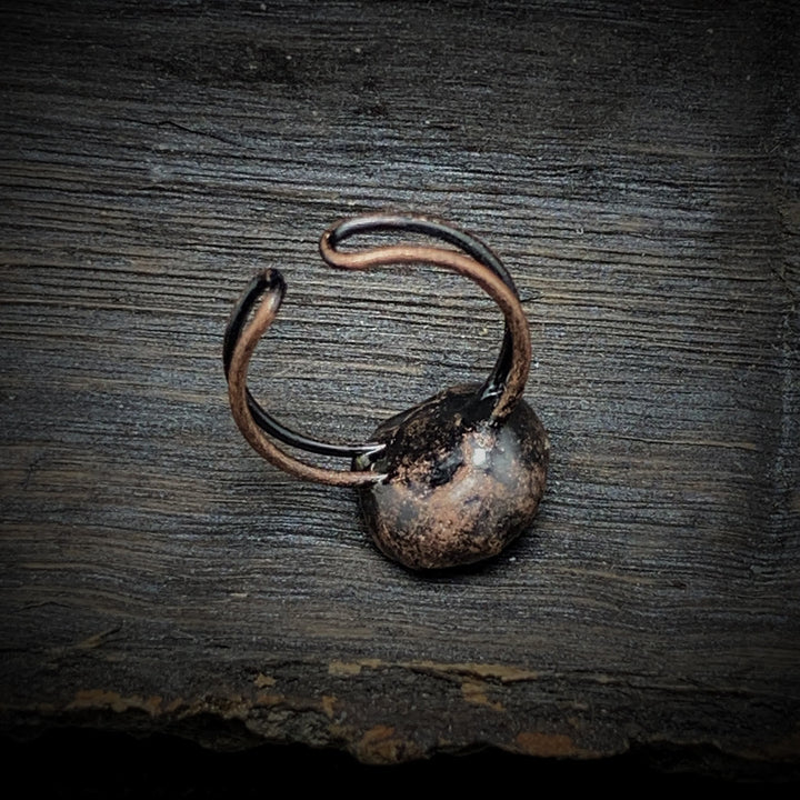 Rustikaler, handgefertigter Kupferring auf Holzoberfläche, Vintage-Schmuck, Unikat.