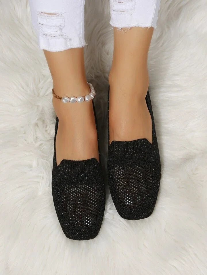 Schwarze Damen-Loafer aus Strick, quadratische Spitze, elegant, bequem, auf weißem Teppich.