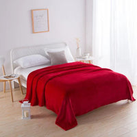 Rotes Fleeceplaid auf weißem Bett, modernes Schlafzimmer, gemütliche Einrichtung, Tagesdecke.