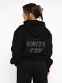 Frau in schwarzem Hoodie mit "White Fox" Aufdruck, Kapuze, lässiger Stil, Streetwear-Mode.