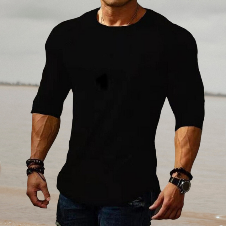 Mann in schwarzem T-Shirt, muskulös, am Strand, modisch, lässig, Herrenbekleidung.