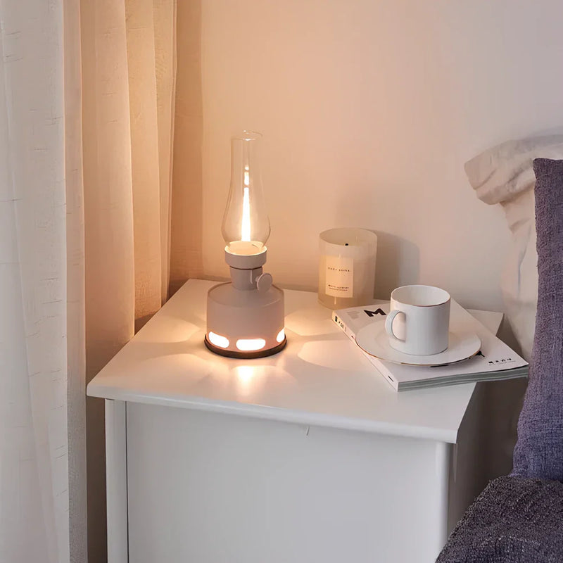 Graue Tischlampe im Vintage-Stil auf Nachttisch, neben Kerze und Tasse, gemütliche Schlafzimmer-Deko.