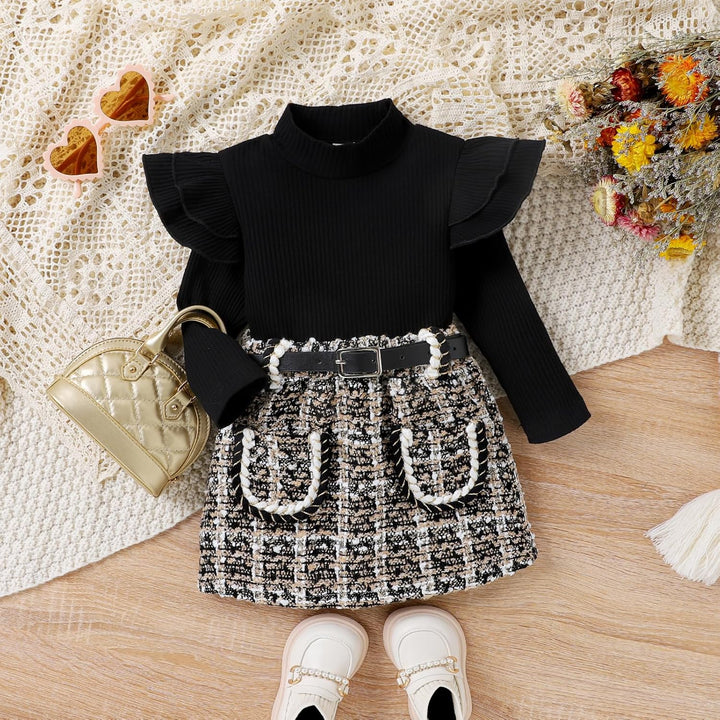 Schwarzes Rüschenkleid für Mädchen mit kariertem Rock, goldener Tasche und weißen Schuhen.