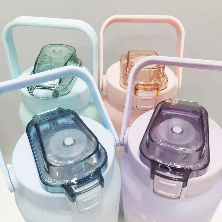 Vier bunte Kunststoff-Wasserflaschen mit Griffen und transparenten Deckeln, pastellfarben.