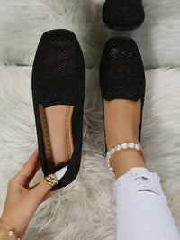 Schwarze Damen-Loafer, glitzernd, auf weißem Teppich, modisch, elegant, bequem.