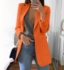 Frau in orangefarbenem Blazer, grauem Top und Jeans, modisch, stilvoll, Spiegel-Selfie.