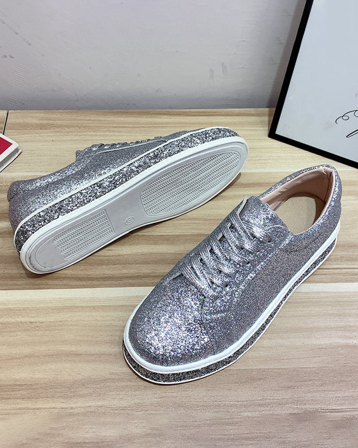 Silberne Glitzersneaker auf Holztisch, modische Damen-Schuhe, glänzend, lässig, bequem.