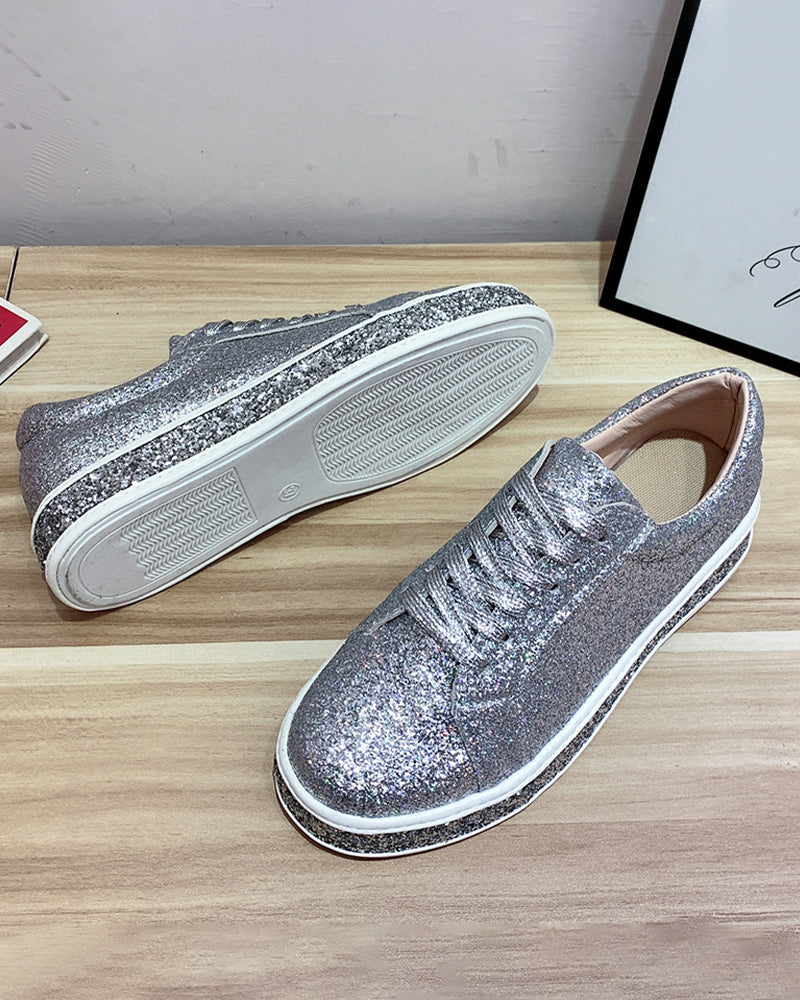 Silberne Glitzersneaker auf Holztisch, modische Damen-Schuhe, glänzend, lässig, bequem.