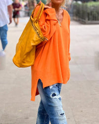 Frau in orangefarbenem Pullover, zerrissene Jeans, gelbe Tasche, lässige Straßenmode.
