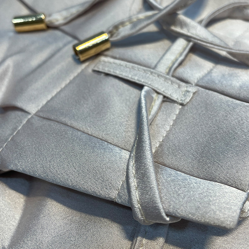 Seidene, silberne Korsett-Oberfläche mit goldenen Kordelenden, luxuriöses Design.