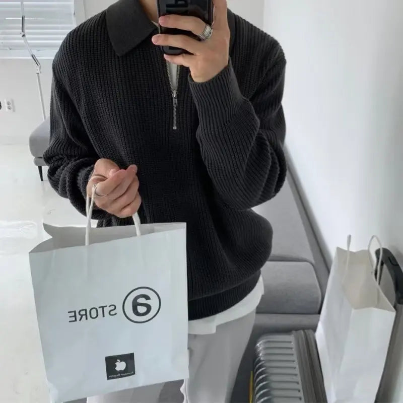 Person in schwarzem Strickpullover mit weißer Einkaufstasche, modernes Interieur.