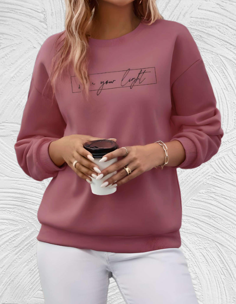 Frau in rosa Pullover mit Schriftzug, hält weißen Kaffeebecher, modisch, lässig, Herbstmode.