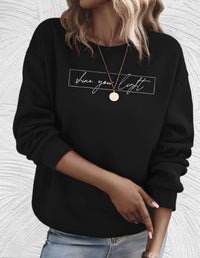 Frau in schwarzem Sweatshirt mit "shine your light" Aufdruck, goldene Halskette, lässiger Stil.