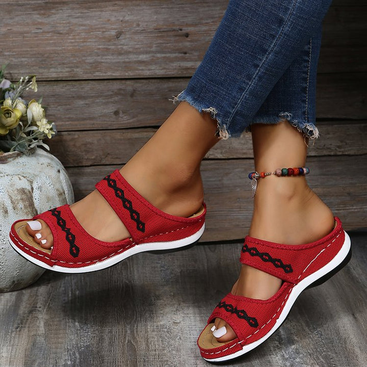 Rote Damen-Sandalen mit Kettendetails, bequem, modisch, Sommer, Jeans, Holzoptik-Hintergrund.