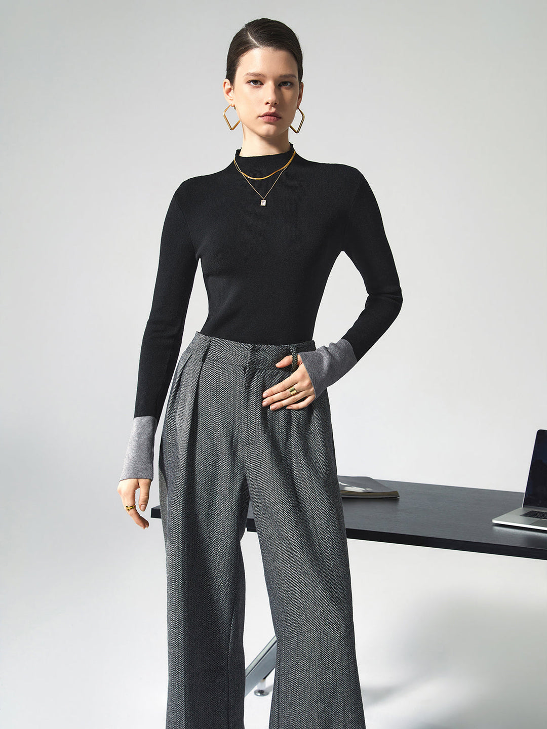 Frau in schwarzem Pullover und grauer Hose, Büro-Outfit, moderne Mode, eleganter Stil.