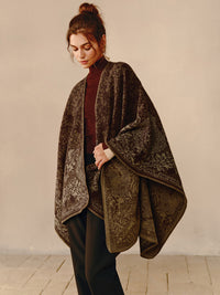 Frau trägt braunen Poncho mit floralem Muster, elegantes Design, Herbstmode, Damenbekleidung.