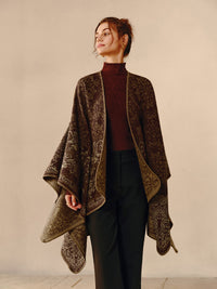 Frau trägt braunen Poncho mit Paisley-Muster, elegantes Herbstoutfit, Damenmode, Strickbekleidung.