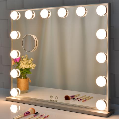 Großer beleuchteter Schminkspiegel mit LED-Lichtern, Blumen und Make-up-Pinseln auf Tisch.