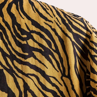 Tigerstreifen-Muster auf gelbem Stoff, modisch, Textildesign, trendig, auffällig.