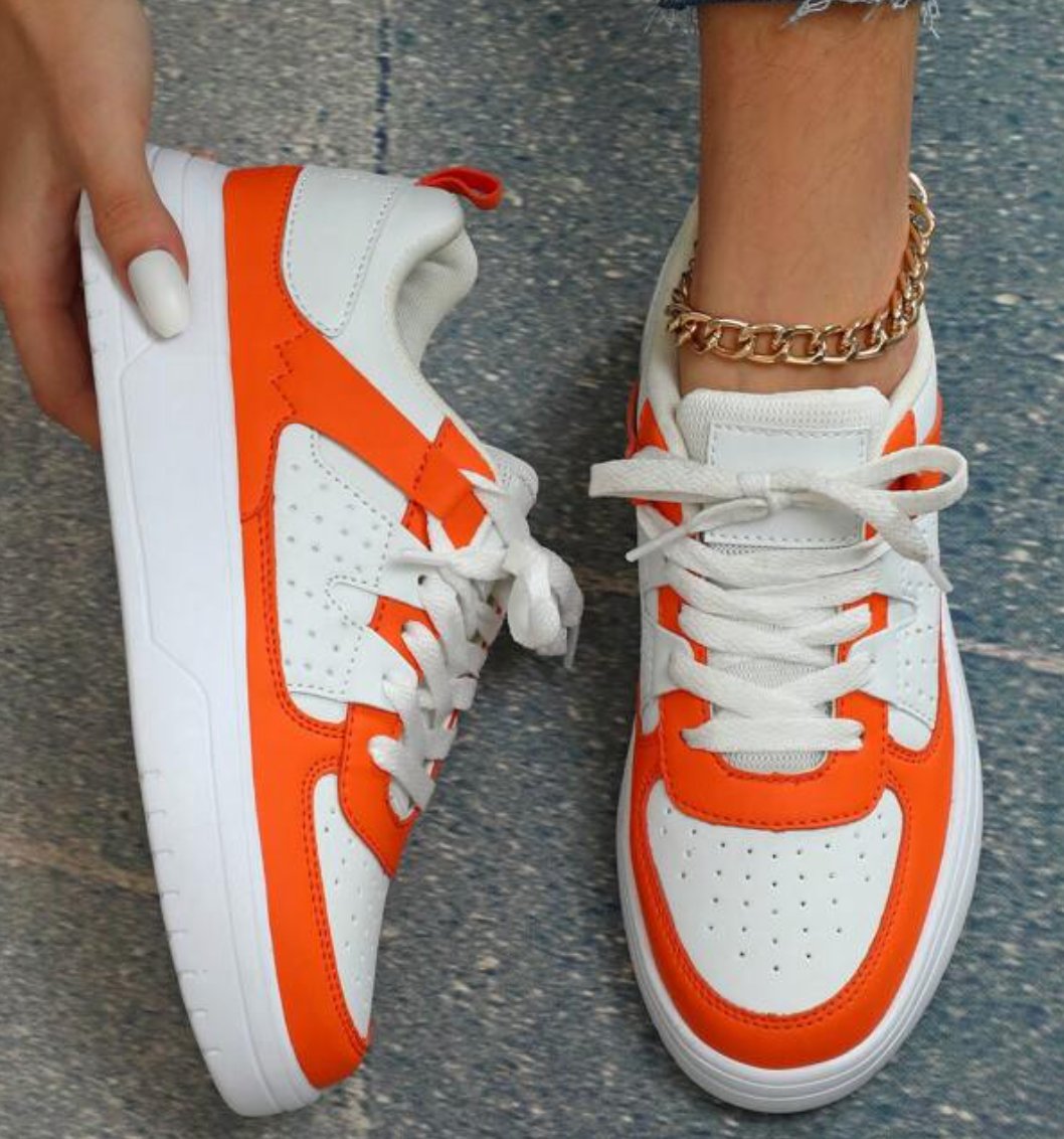 Weiße und orange Sneaker, Damen, Leder, sportlich, modisch, Straßenstil, Nahaufnahme.