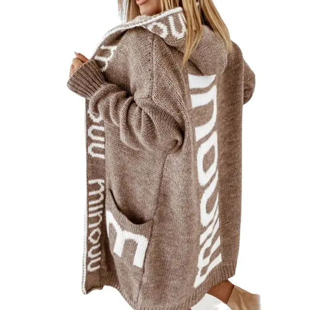 Frau in braunem Strickmantel mit Kapuze und Schriftzug, modisch, gemütlich, Herbstbekleidung.