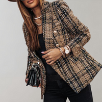 Frau in kariertem Tweed-Blazer, schwarz-gold, mit Uhr und Tasche, modisch elegant.