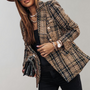 Frau in kariertem Tweed-Blazer, schwarz-gold, mit Uhr und Tasche, modisch elegant.