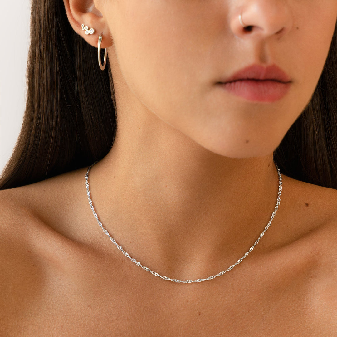 Frau mit silberner Halskette und Ohrringen, minimalistisch, Schmuck, Modeaccessoire, Nahaufnahme.
