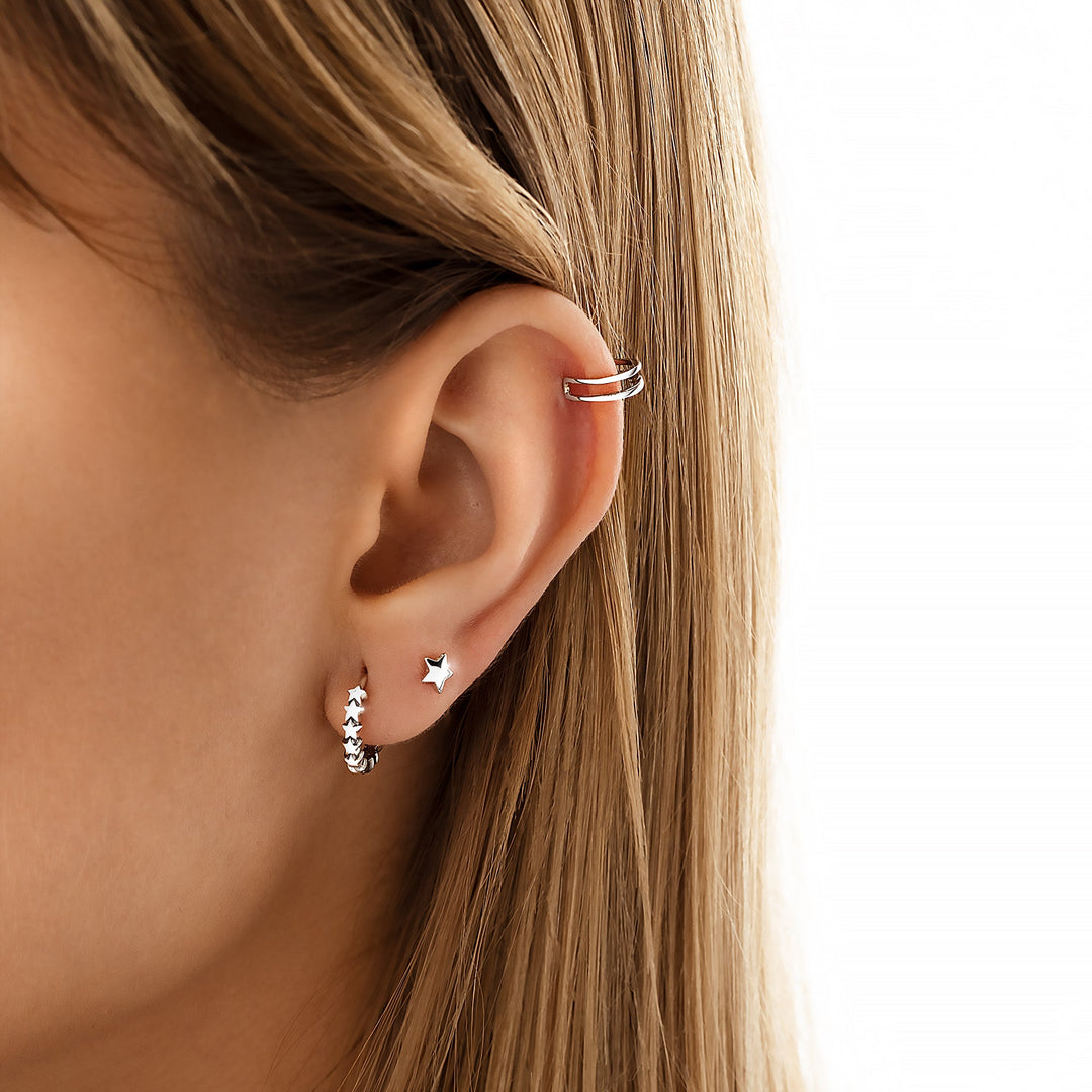 Frau mit silbernen Ohrringen und Ohrmanschette, Stern-Design, modischer Schmuck, Nahaufnahme.