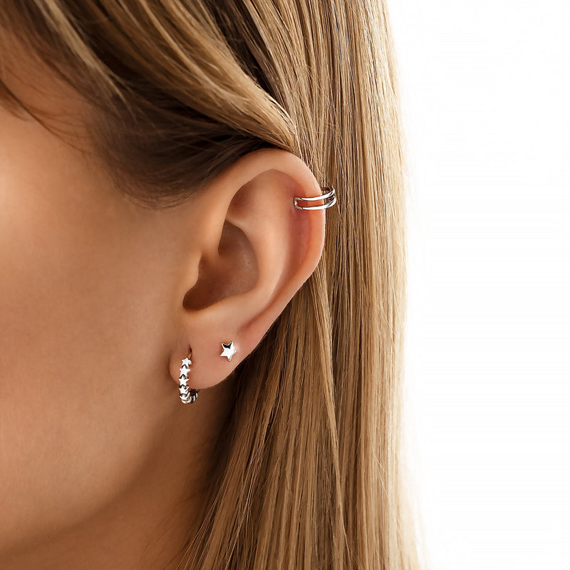 Frau mit silbernen Ohrringen und Ohrmanschette, Stern-Design, modischer Schmuck, Nahaufnahme.