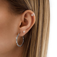 Frau mit silbernen Creolen, Ohrstecker und goldfarbenem Ohrklemmen, Nahaufnahme, Schmucktrends.