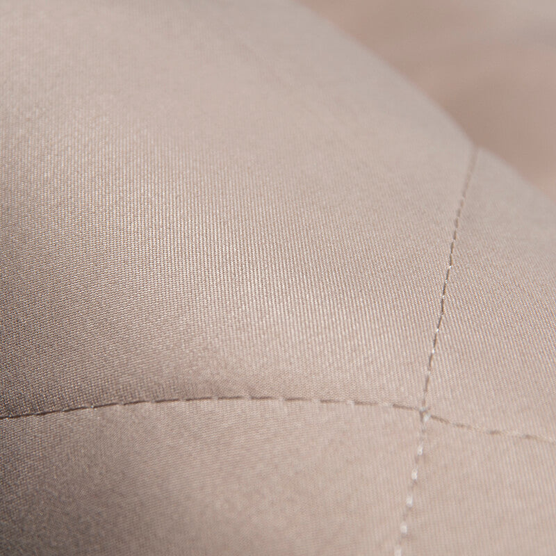 Beigefarbener, gesteppten Stoff, Nahaufnahme, Textur, Polstermaterial, hochwertig, Detailansicht.